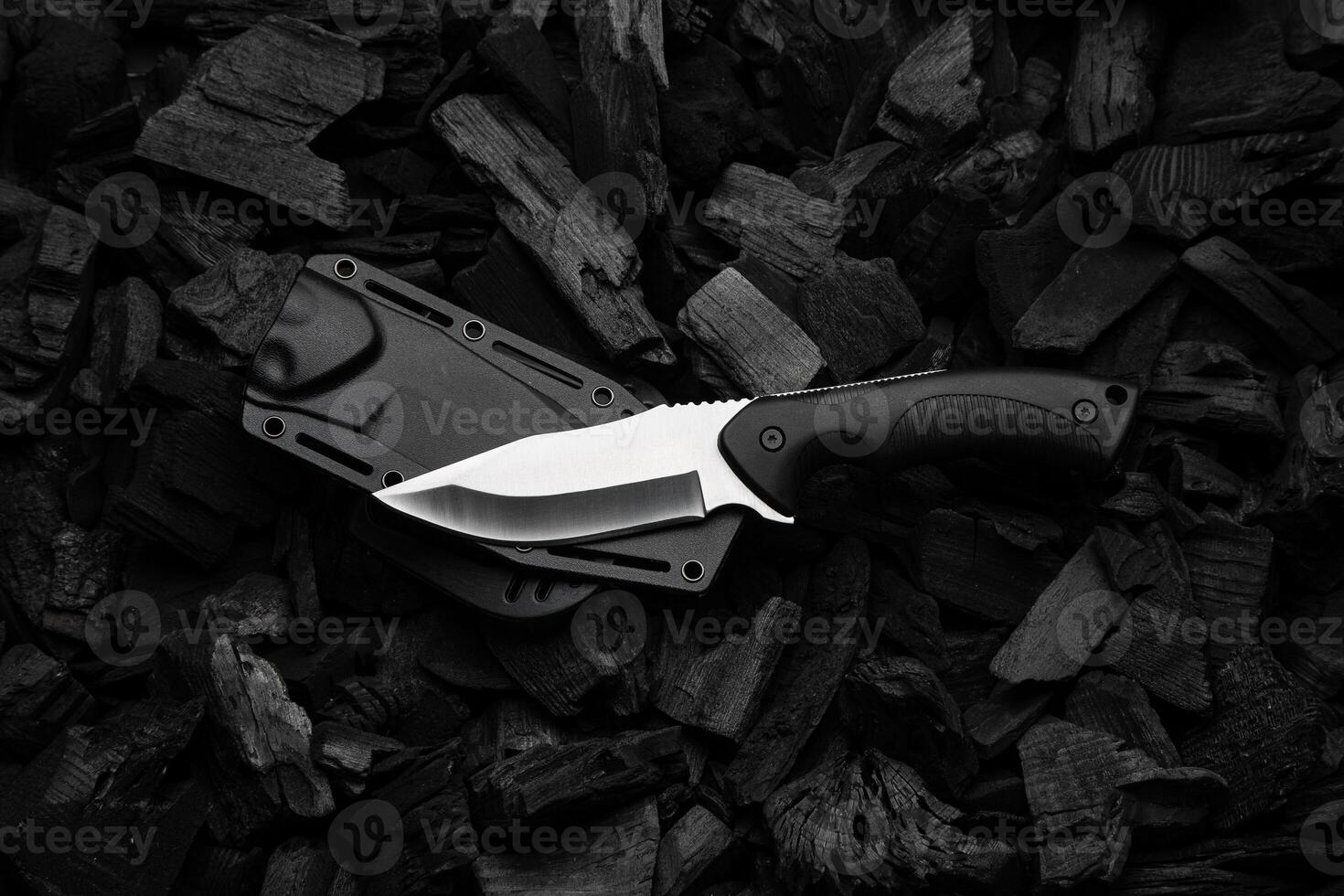 A modern knife with a silver blade and a rubberized handle. Plastic scabbard. Dark charcoal back. photo