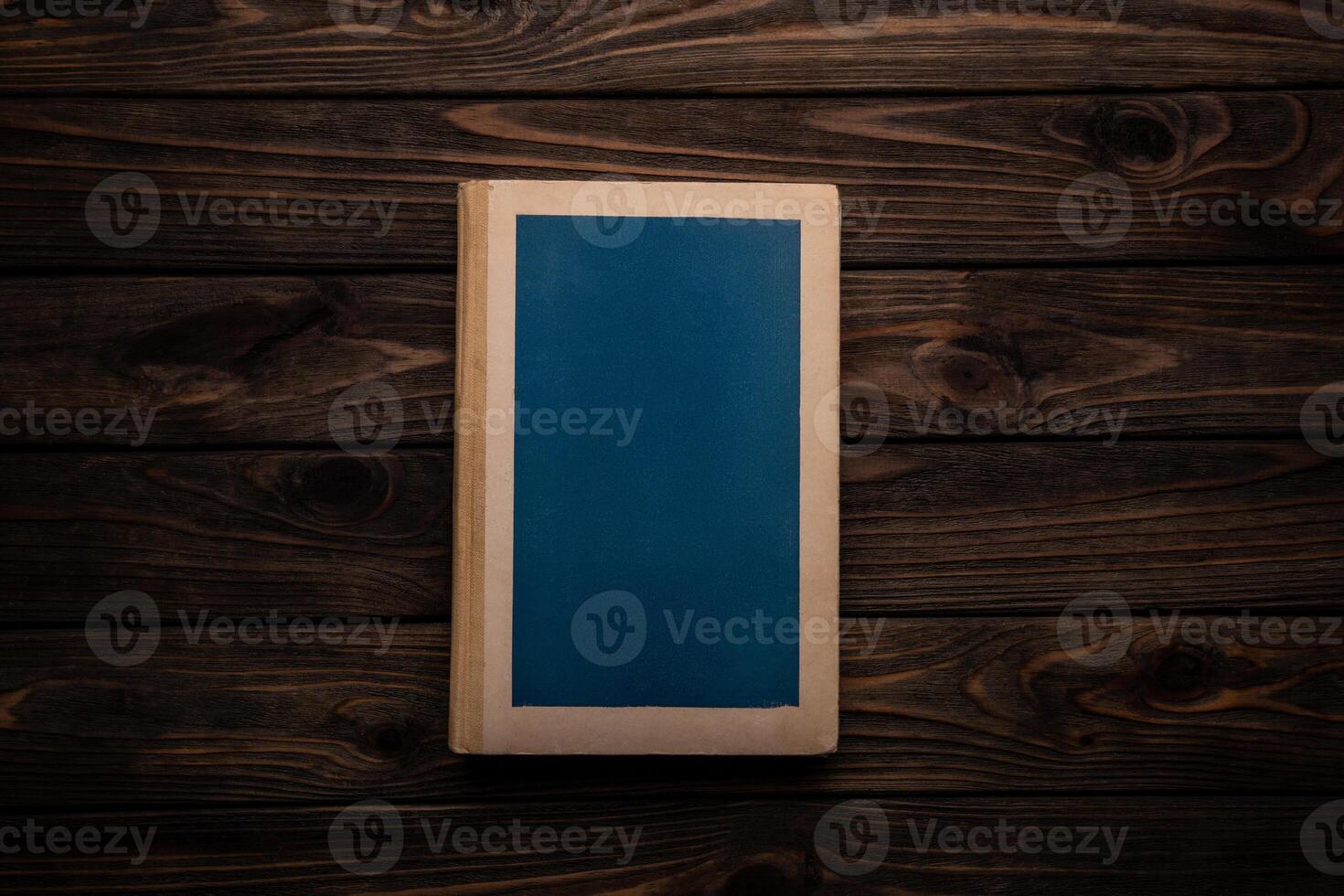 Closed book on vintage wooden back. Old book on the wooden table. Closed book with empty cover laying on wooden table. photo