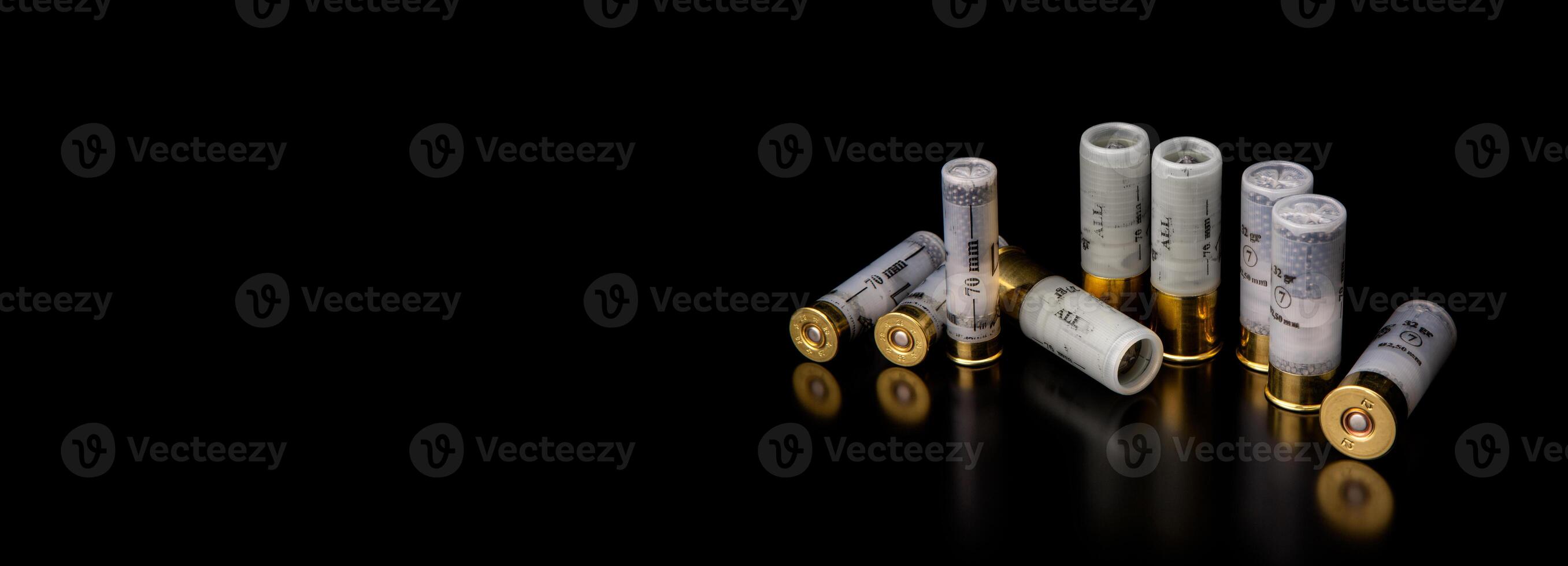 Shotgun cartridges on a dark surface with reflections. Ammunition for smooth-bore weapons on a black back photo