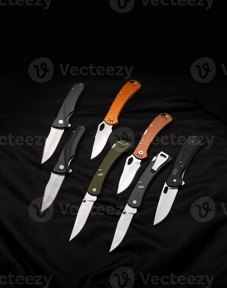 Various folding pocket knives on a dark back. A versatile pocket tool and self-defense tool. photo