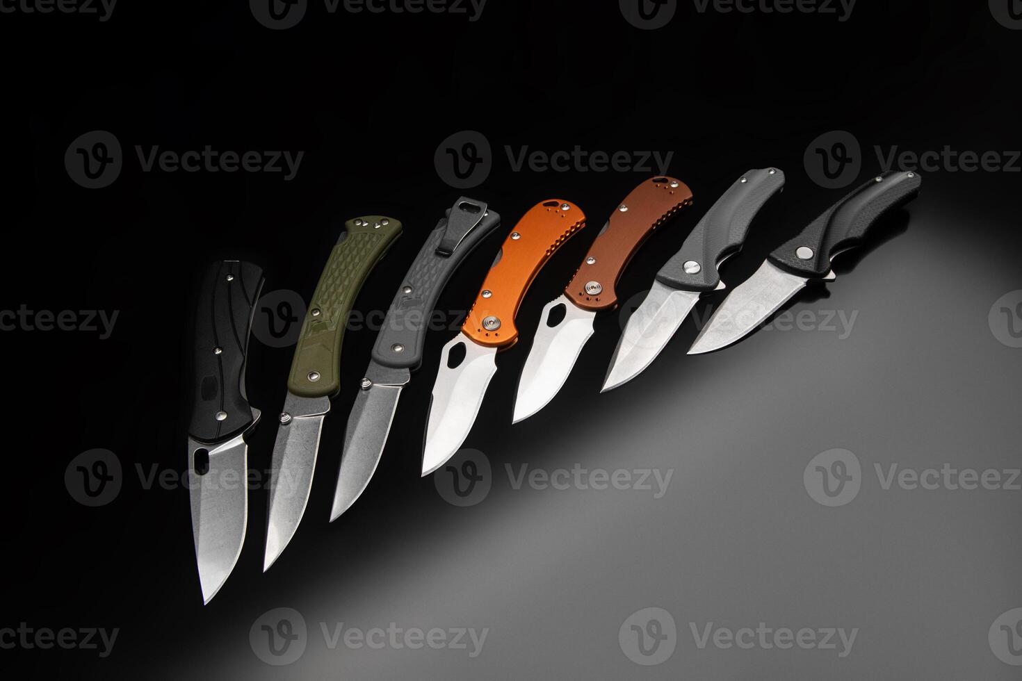 Various folding pocket knives on a dark back. A versatile pocket tool and self-defense tool. photo