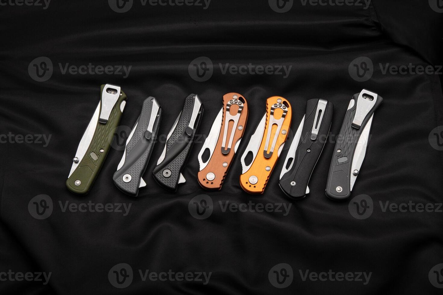Various folding pocket knives on a dark back. A versatile pocket tool and self-defense tool. photo