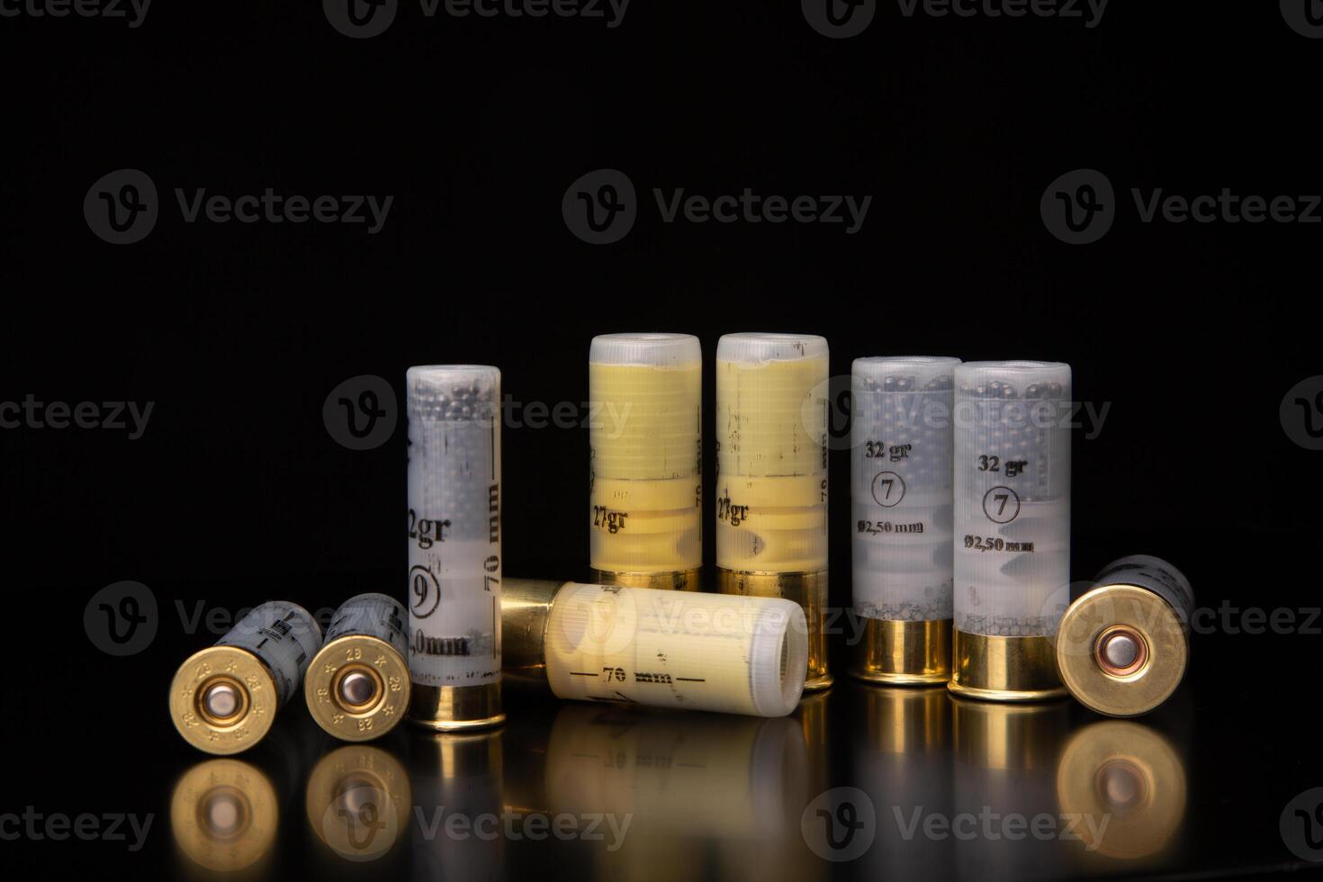 Shotgun cartridges on a dark surface with reflections. Ammunition for smooth-bore weapons on a black back photo