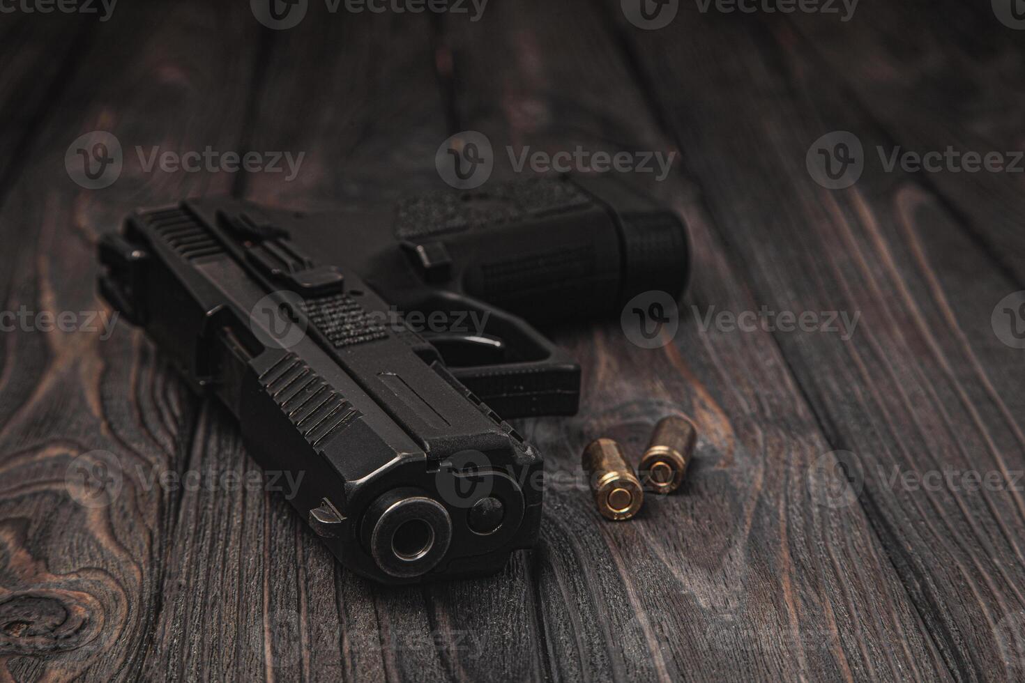 Pistol and cartridges for it on a wooden background. A short-barreled weapon for self-defense photo