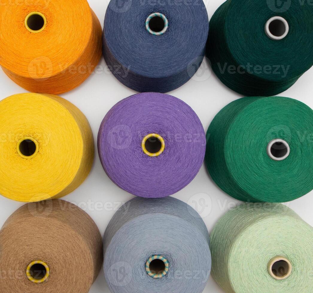 Multi-colored bobbins of yarn on a white background. Top view on colored spools of thread.Textile reels on white background. photo
