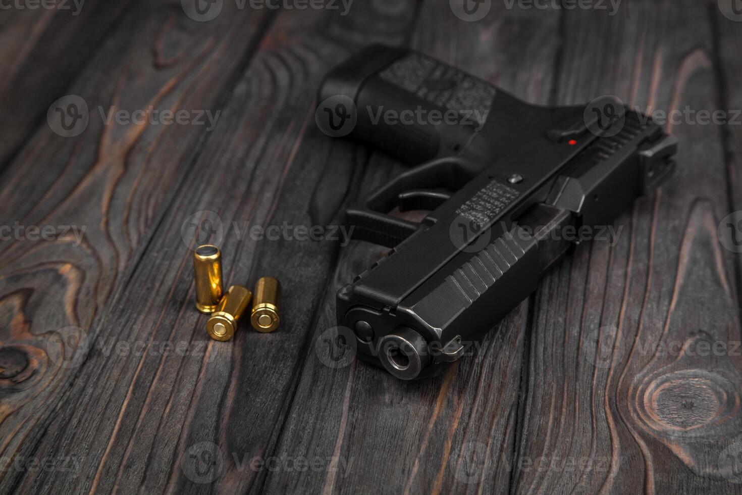 black pistol and cartridges on a wooden background photo