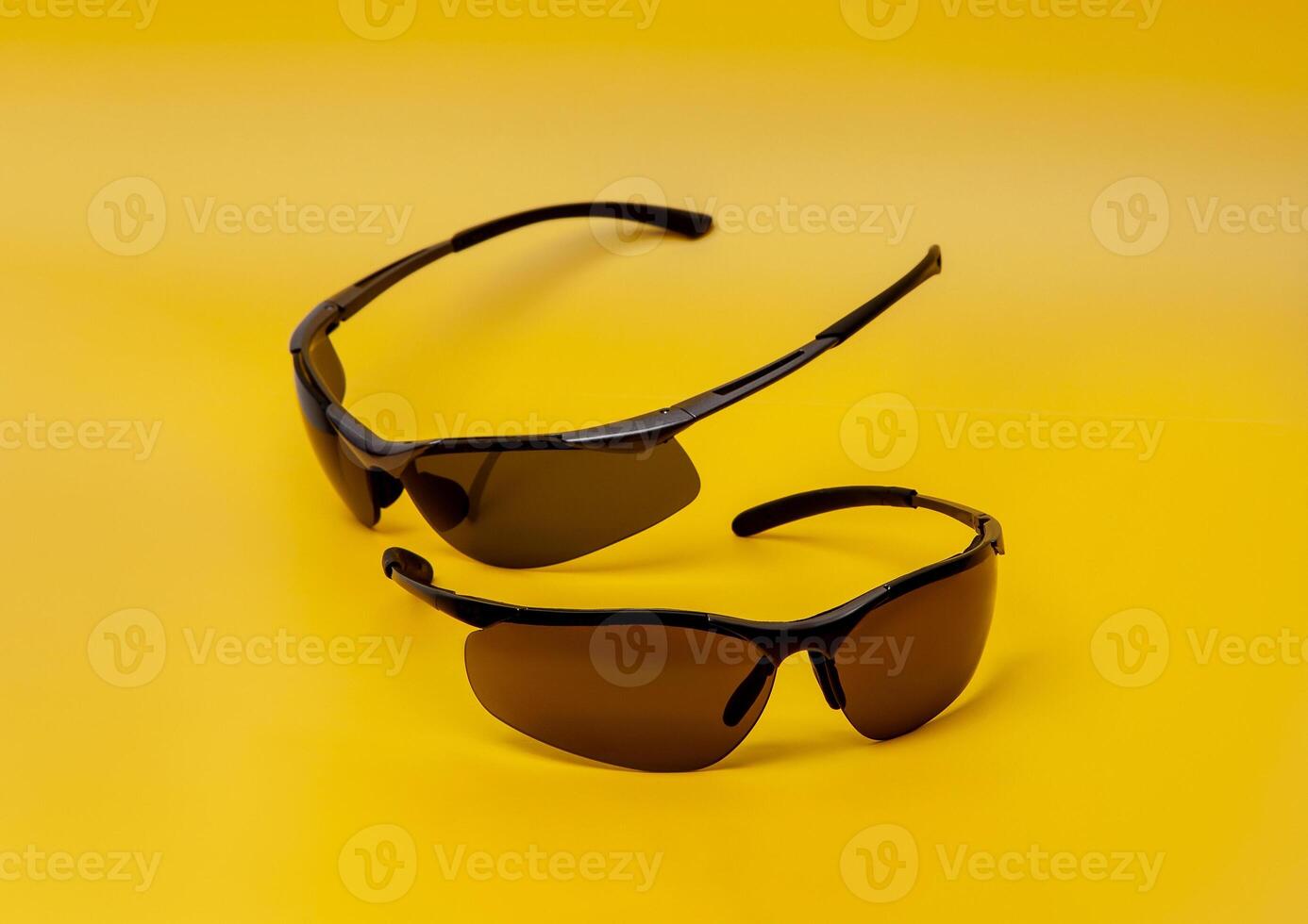Modern safety goggles for athletes and workers. Stylish sports glasses on a colored background. Yellow back. photo