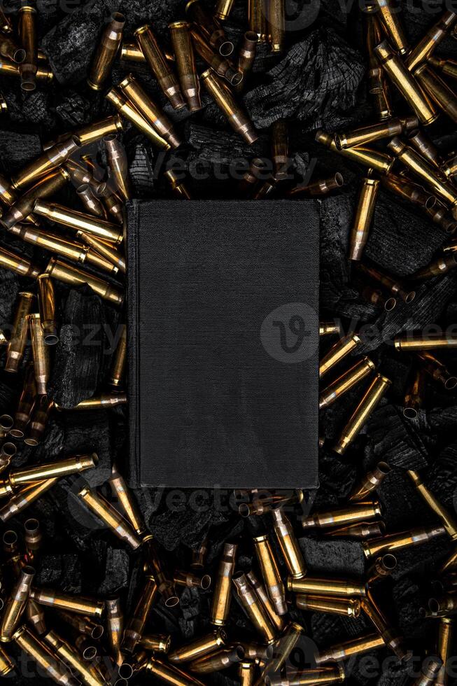 Cover of a black closed book. Empty gun cases lying on charred coals. Dark back. photo