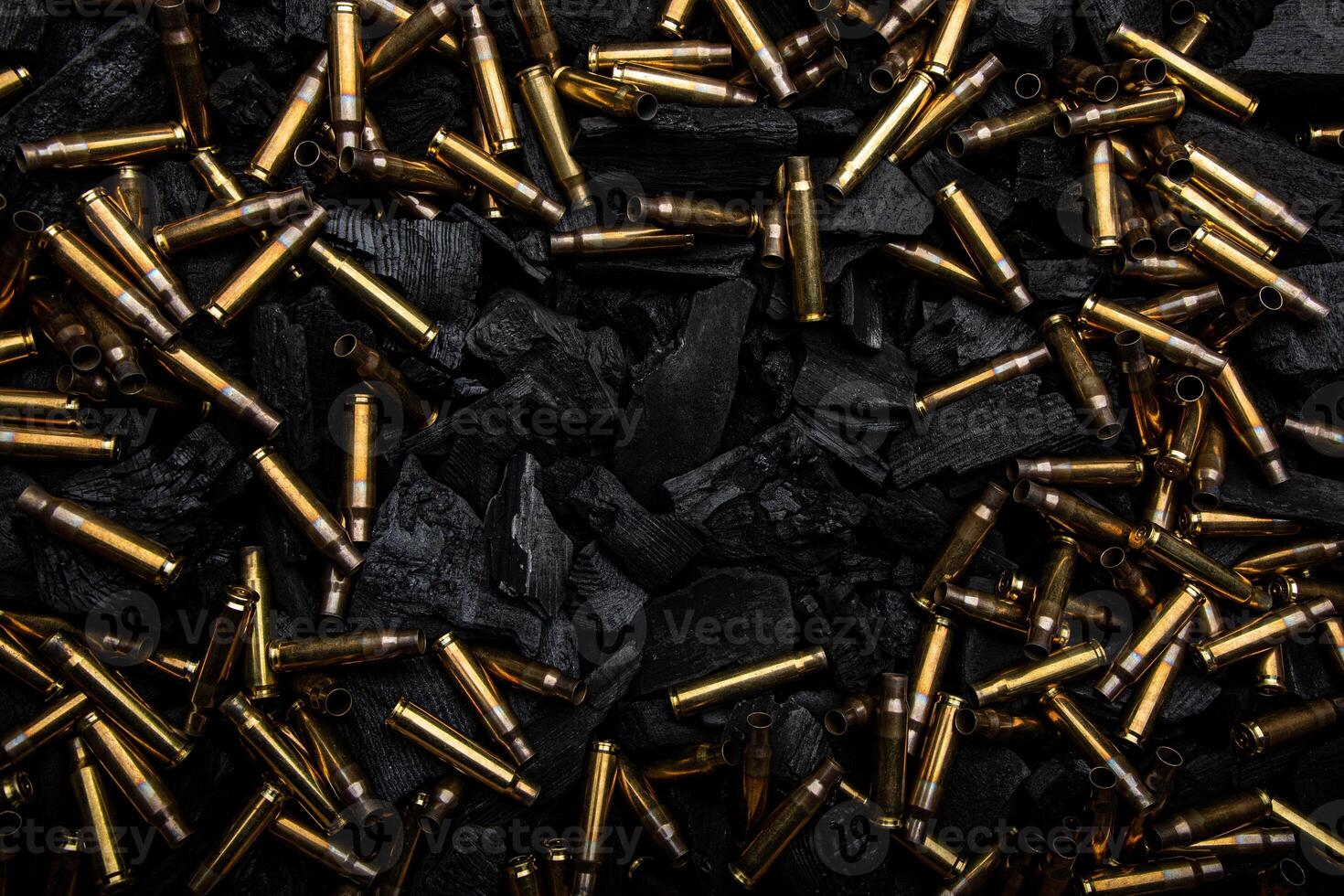 Empty shells from weapons on black smoldering coals. Consequences of the war. Dark back. photo