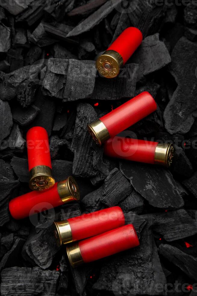 Shotgun cartridges on charcoal. Ammunition for 12 gauge smoothbore weapons. Hunting ammunition. Dark back. photo