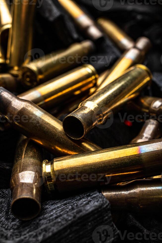 Empty shells from weapons on black smoldering coals. Consequences of the war. Dark back. photo