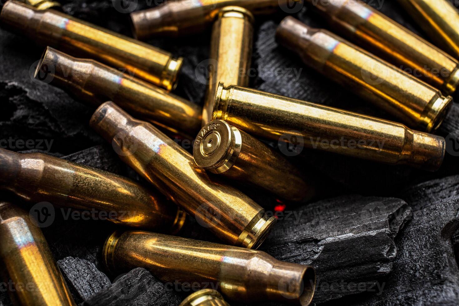 Empty shells from weapons on black smoldering coals. Consequences of the war. Dark back. photo