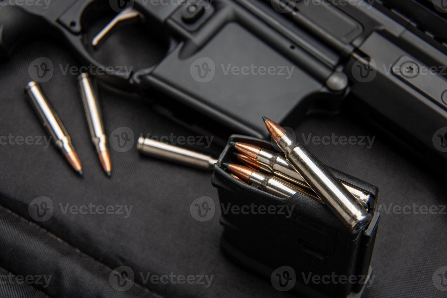 Close-up of .223 carbine cartridges. Loaded weapon clip. Weapons in the back photo