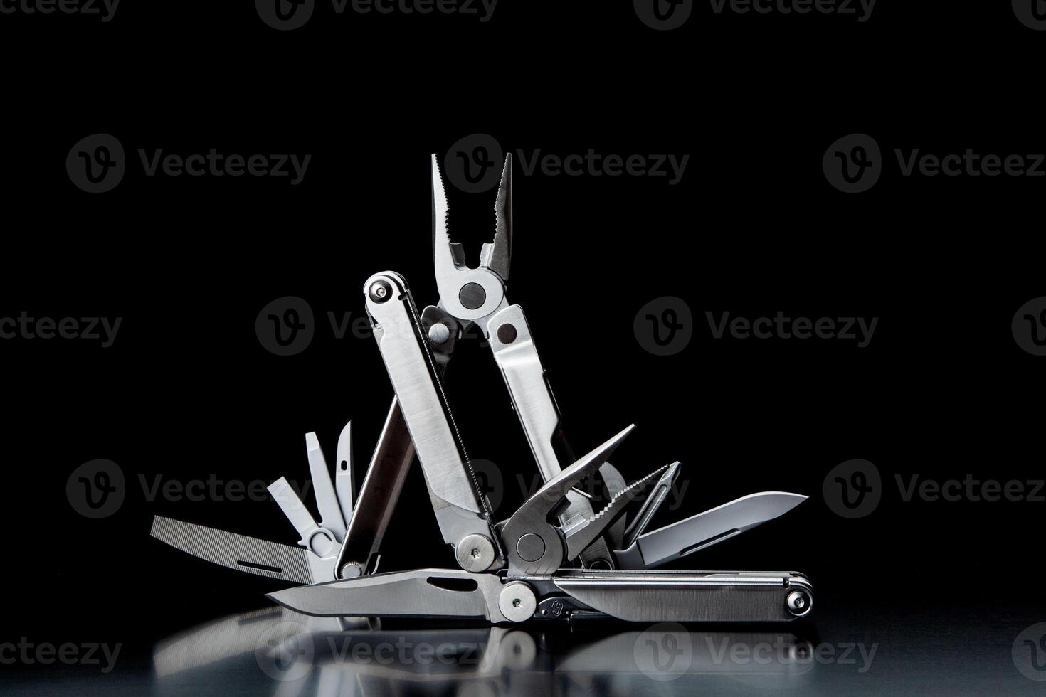 Folding multitools on a dark back. Metal pocket multi-tools. photo