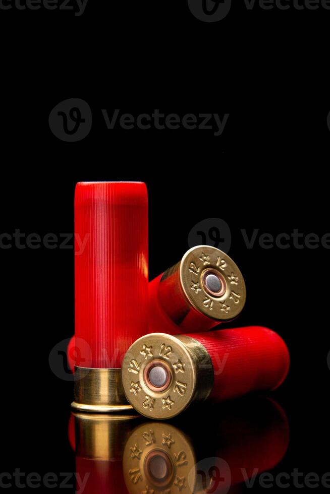 Shotgun shells on a black reflective surface. Ammunition for 12 gauge smoothbore weapons. Hunting ammunition. Dark back. photo