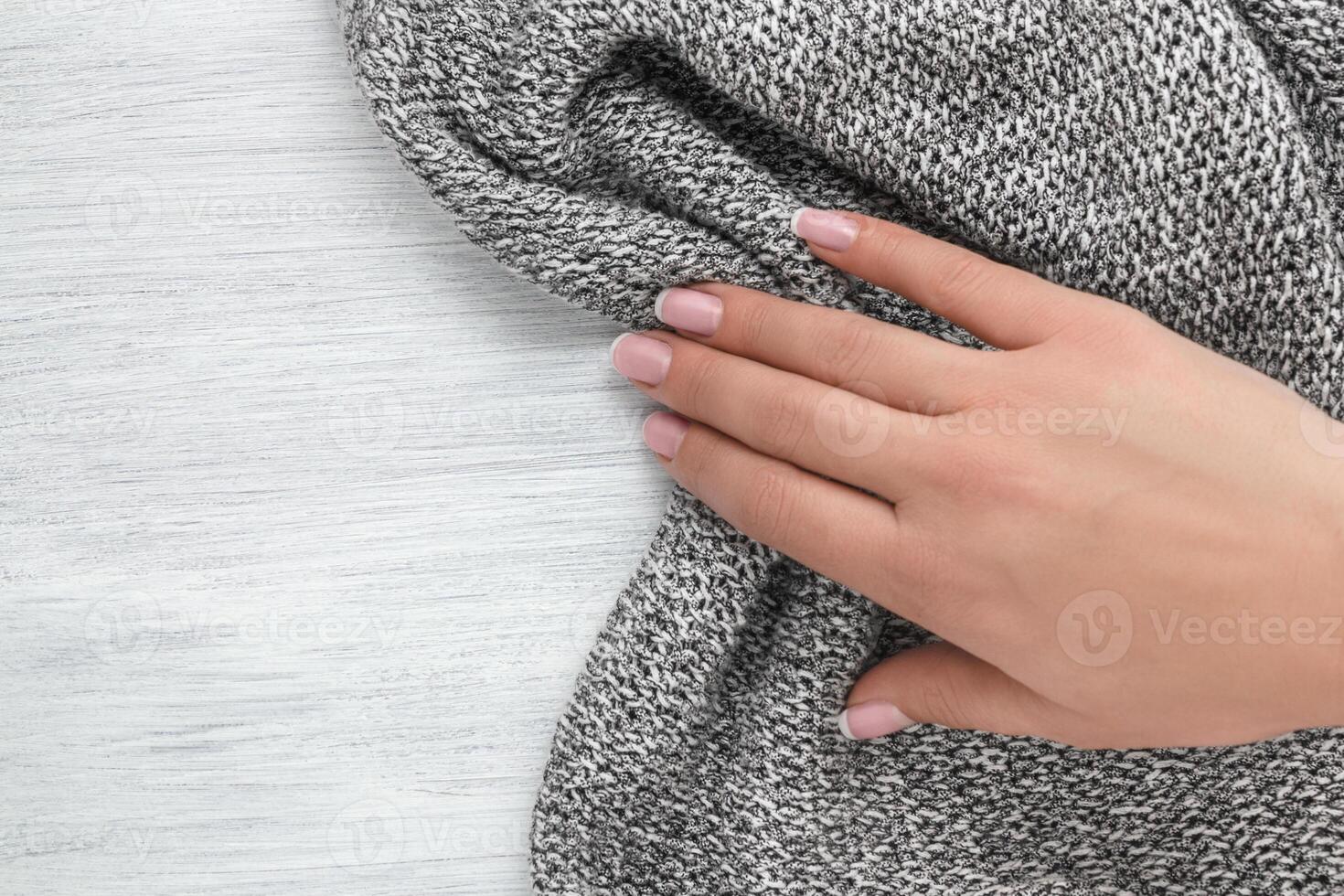 Hand of a young girl pulling out a knitted cloth. Concept of rustic background. photo