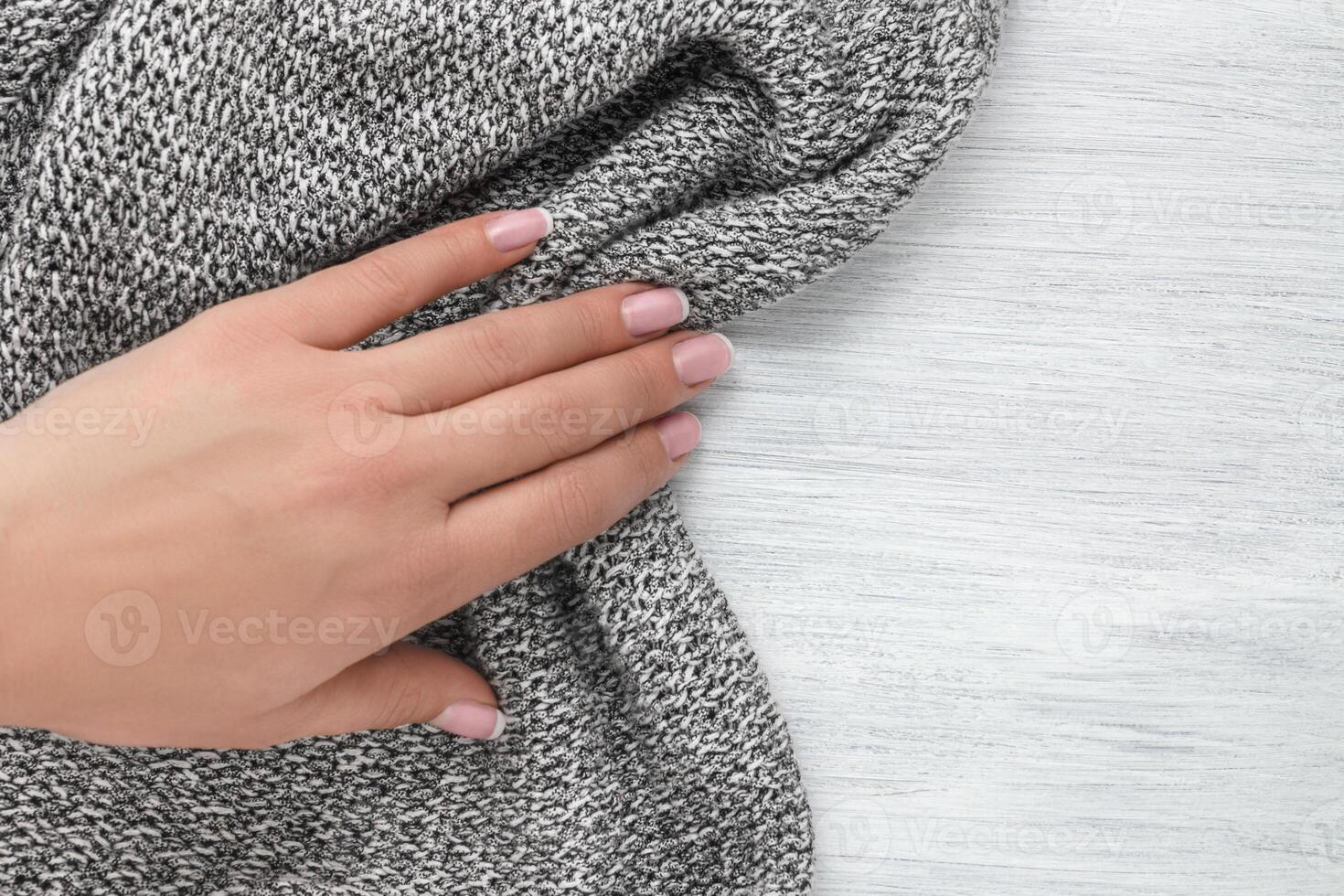 Hand of a young girl pulling out a knitted cloth. Concept of rustic background. photo