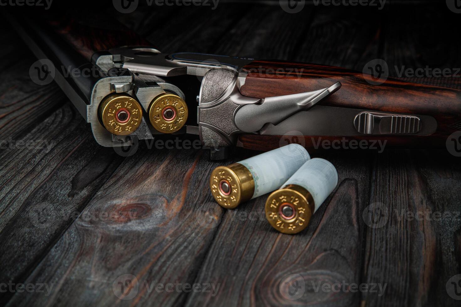 Classic trigger double-barreled hunting rifle on a wooden background. Concept postcards for hunters. Smooth-bore hunting rifle open for reloading. photo