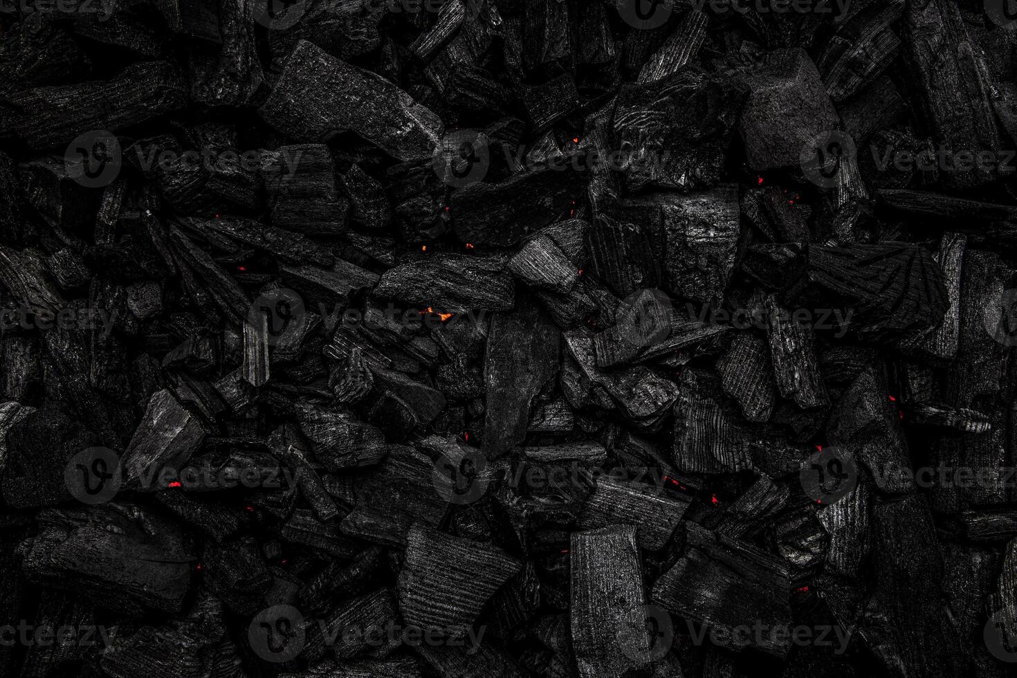 Charcoal with red streaks of heat. Textured dark back. photo