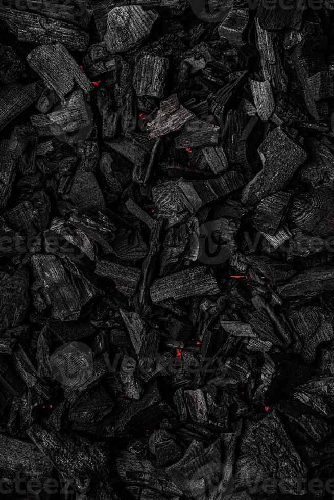 Charcoal with red streaks of heat. Textured dark back. photo