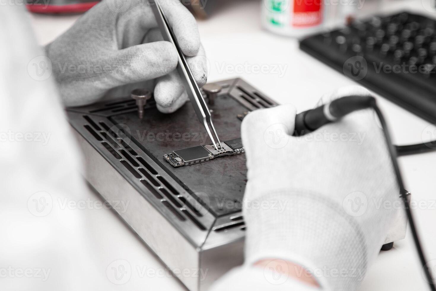 The master solders the microchip.. Service center. Repair of microelectronics. photo