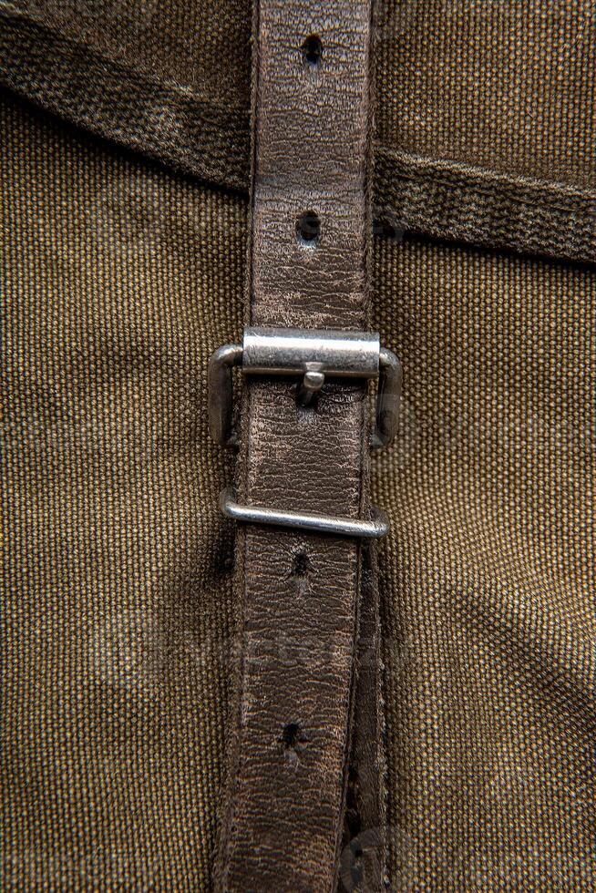 Close-up texture of a canvas fabric backpack. Leather straps and metal buckles. Vintage khaki back. photo