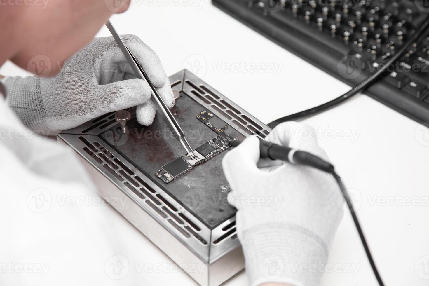 The master solders the microchip.. Service center. Repair of microelectronics. photo
