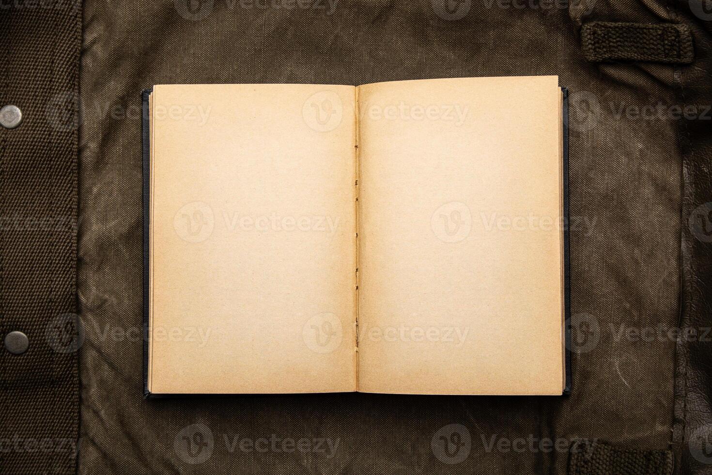 An open book with yellowed pages on an old backpack. Vintage khaki canvas back. photo