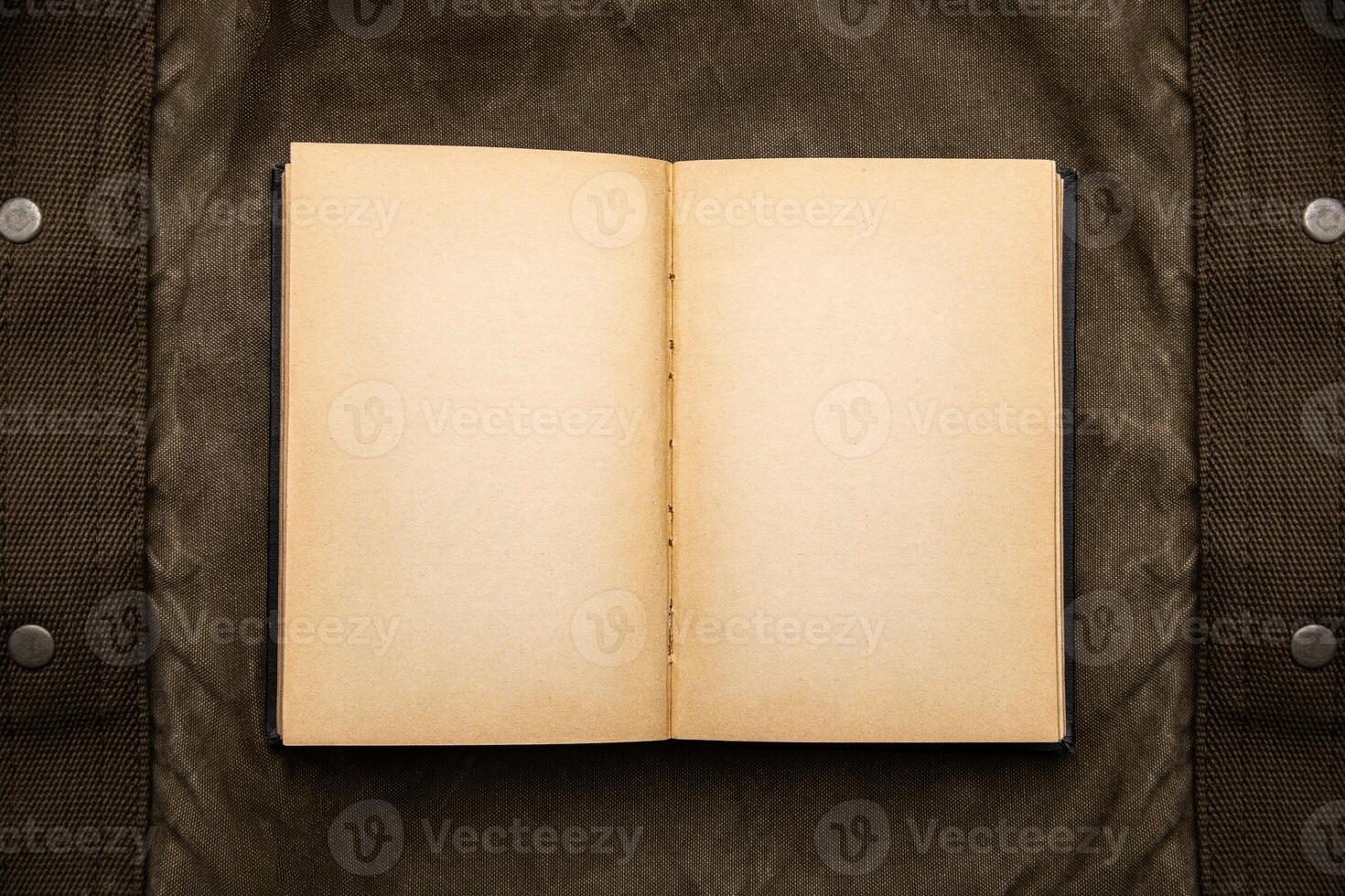 An open book with yellowed pages on an old backpack. Vintage khaki canvas back. photo
