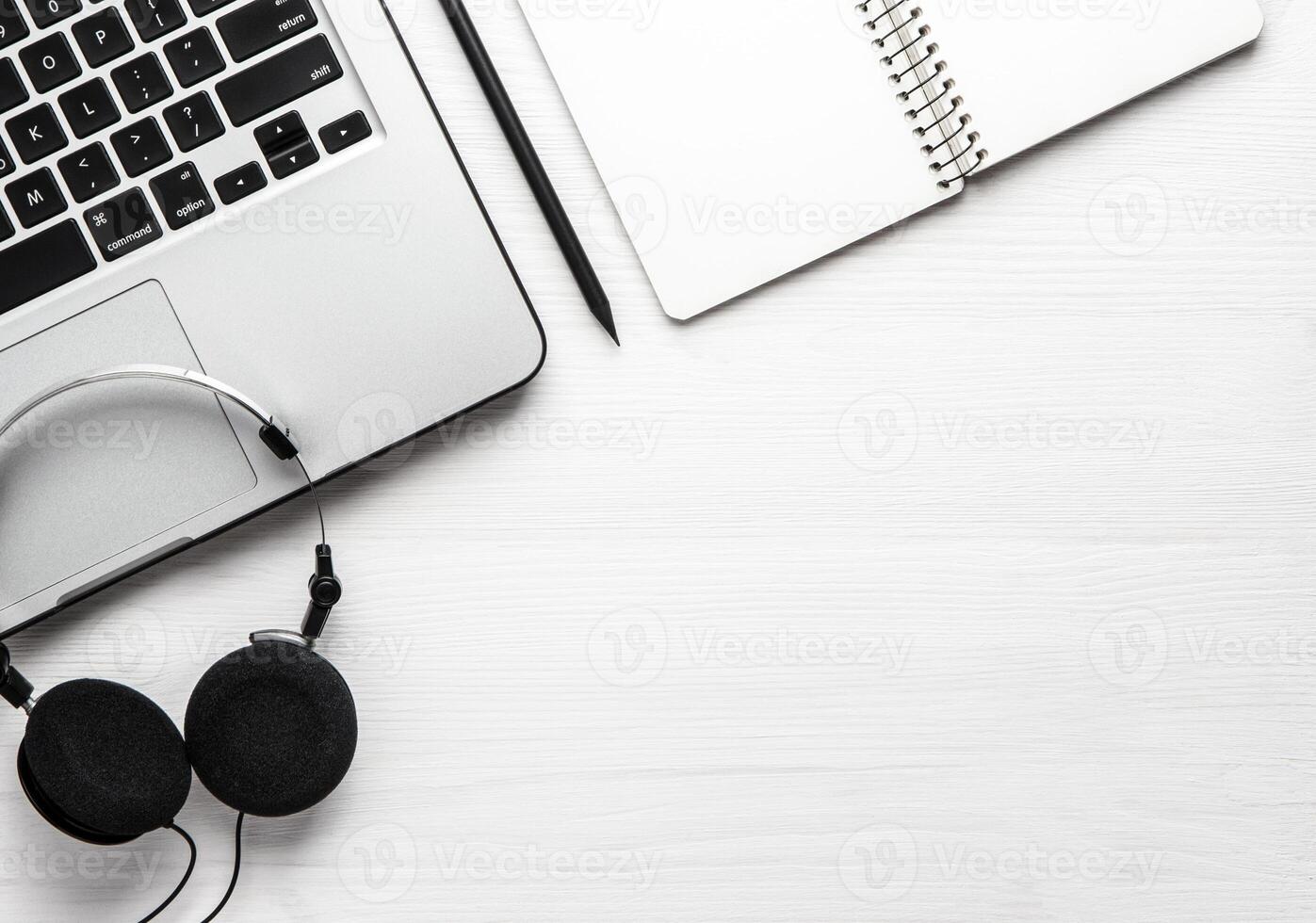 Notebook headphones and laptop on a white wooden background. Flat lay with copy space. photo