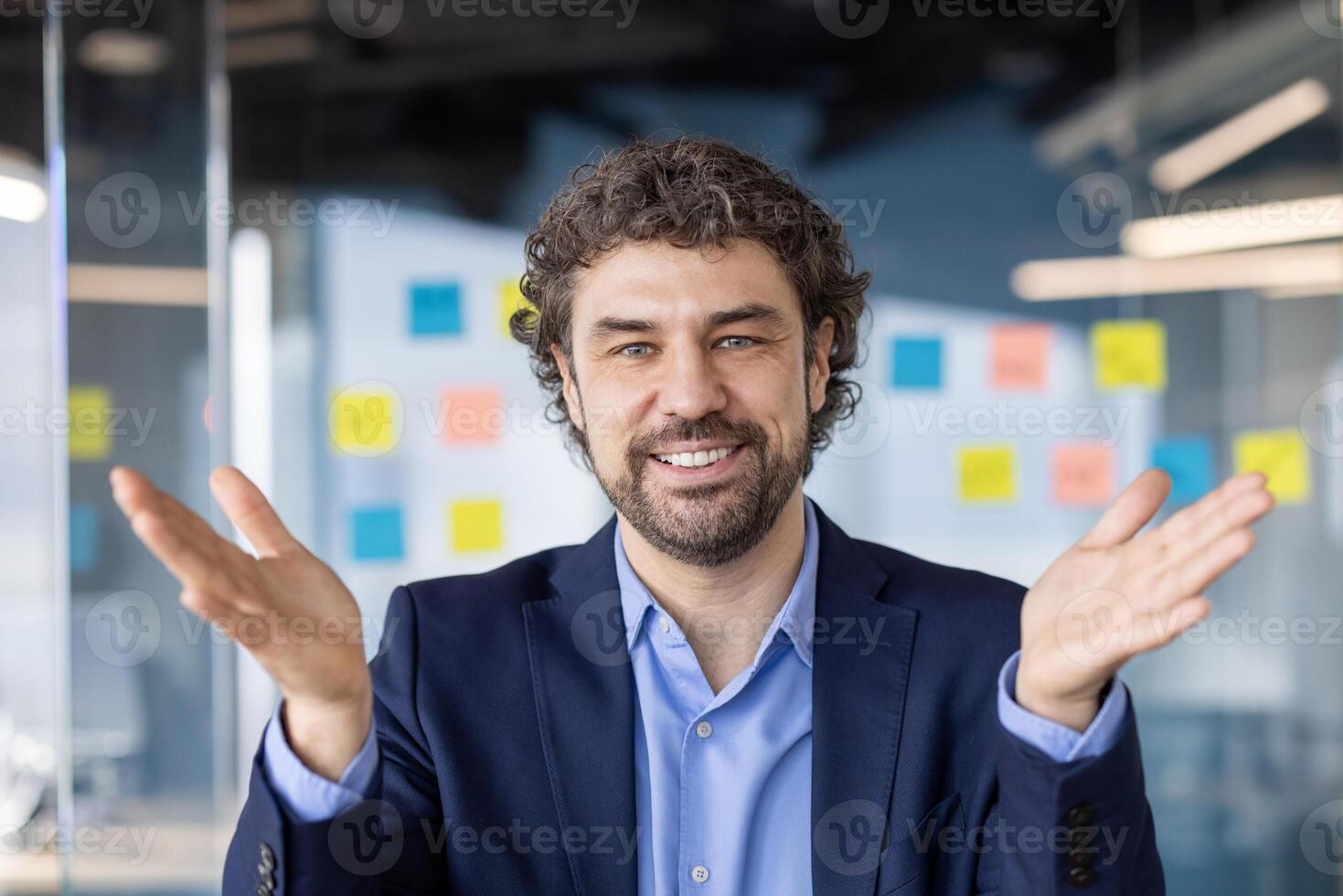 Confident businessman smiling and gesturing while talking during call in contemporary office. Casual conversation, connection, and successful communication concept photo