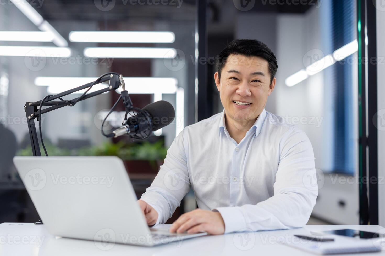 Portrait business coach, male mentor recording audio podcast in studio, businessman working with laptop, using professional microphone, teacher smiling, looking at camera, financier training course. photo