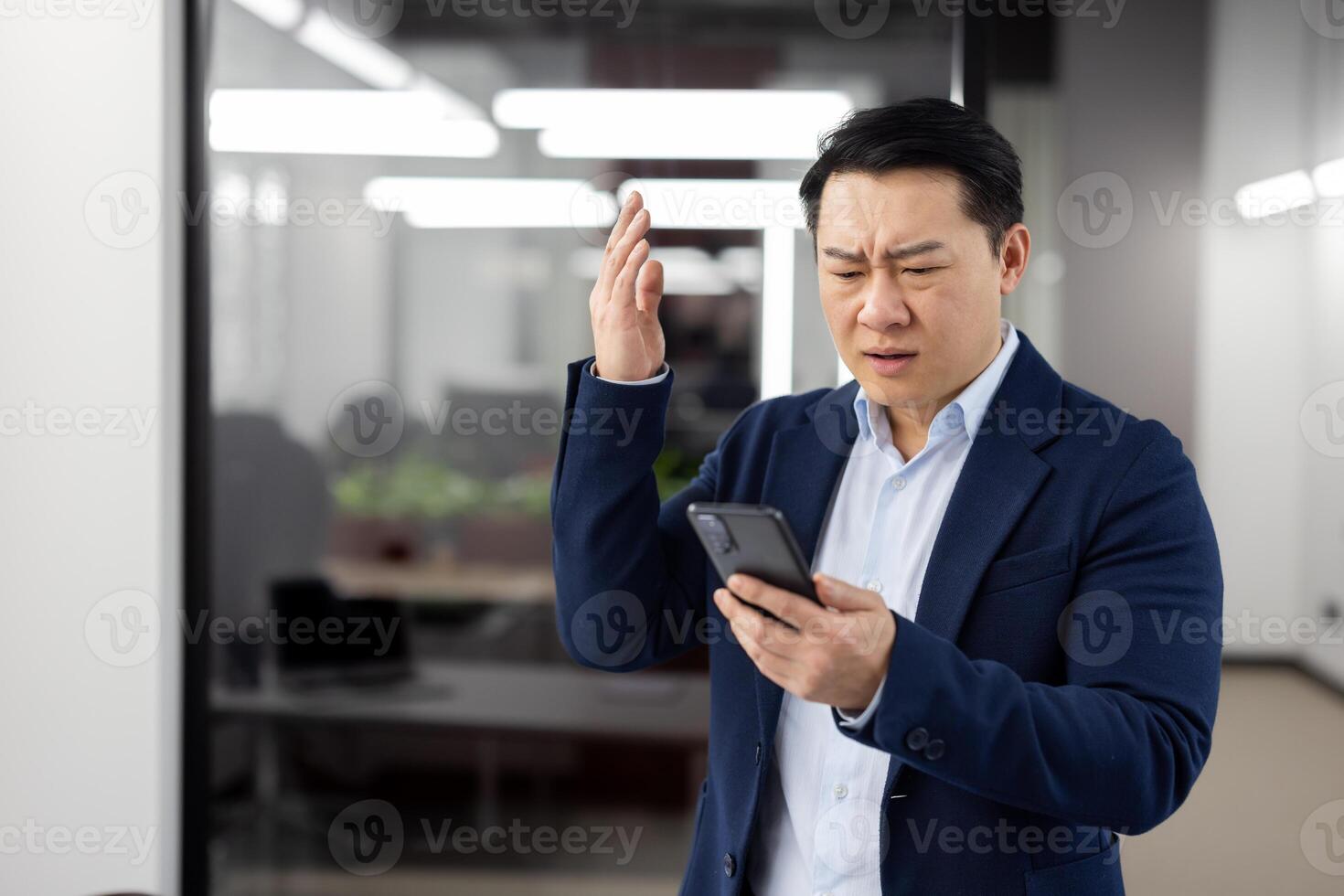 Man in business suit inside office with phone in hands, mature businessman received online notification message with bad news, boss uses app on smartphone, upset received rejection error. photo