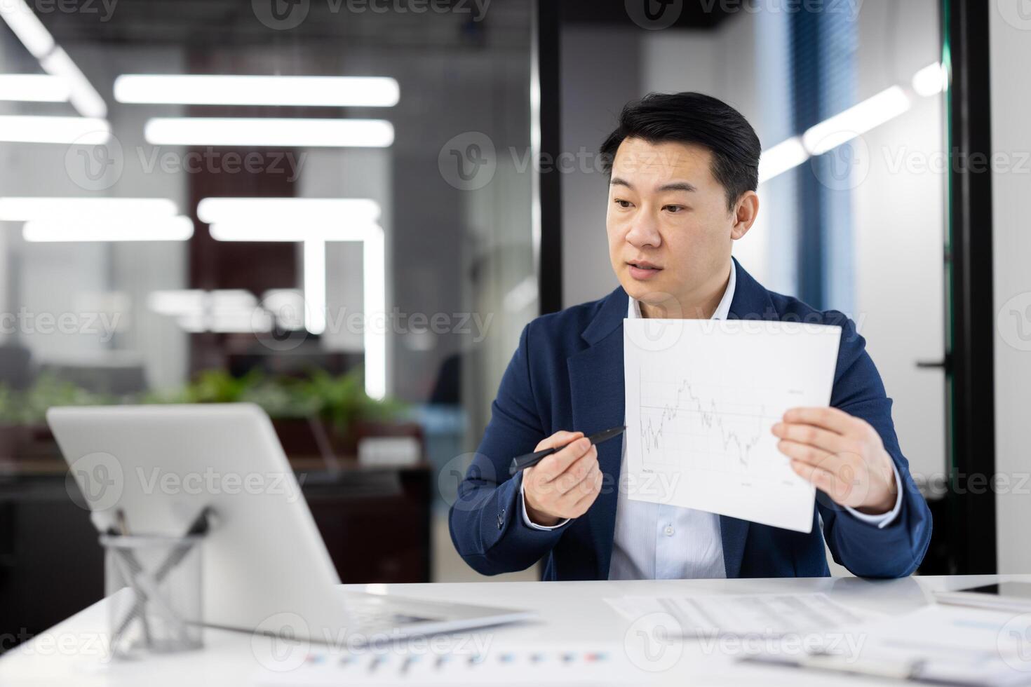Confident Asian businessman presenting a financial chart while conferencing in a well-lit, contemporary office setup. Illustrates corporate analytics and market trends. photo