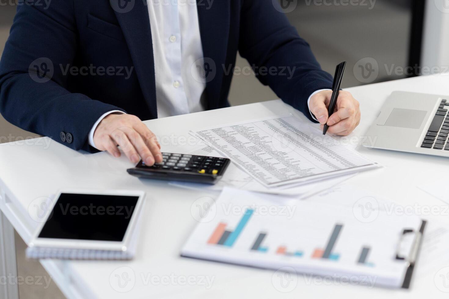 Corporate executive evaluating company finances with charts, tablet, laptop at a modern office workspace. photo