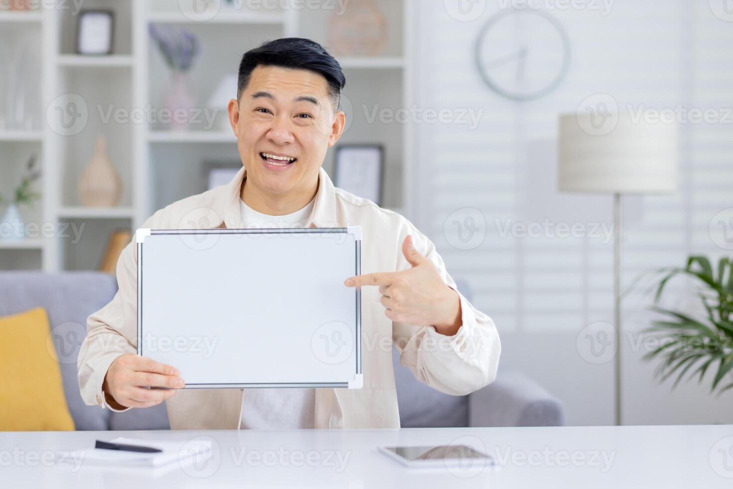 Happy man smiling and pointing at a blank whiteboard in a modern home office environment. Great for messaging, presentations, and promotional content. photo