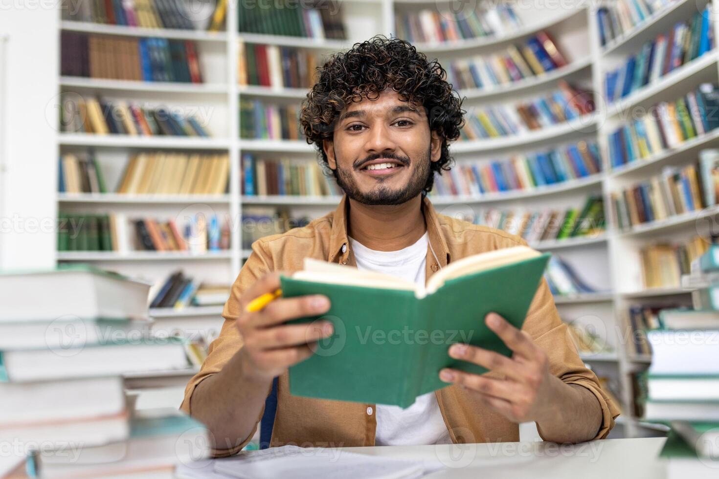 A diligent student engages in intense study at a library, with stacks of books around. The scene depicts preparation for university exams, conveying dedication and the pursuit of knowledge at an academic campus. photo