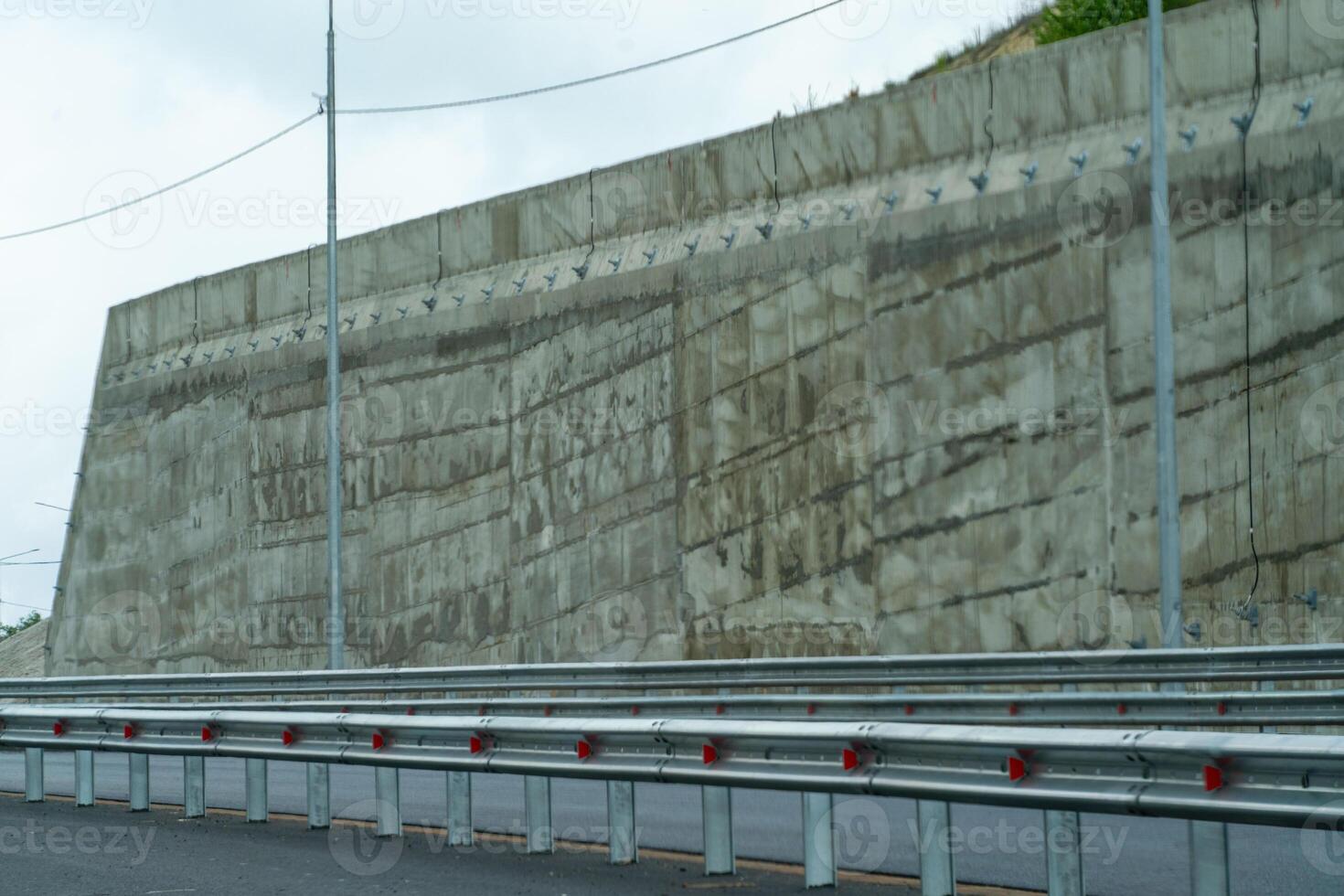 A construction site with scaffolding and orange cones. The orange cones are placed in a row along the road. photo