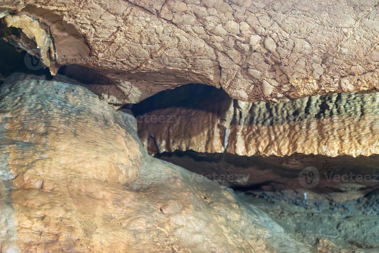 A rock wall with a brown and tan color. The wall is made of rocks and has a rough texture. photo