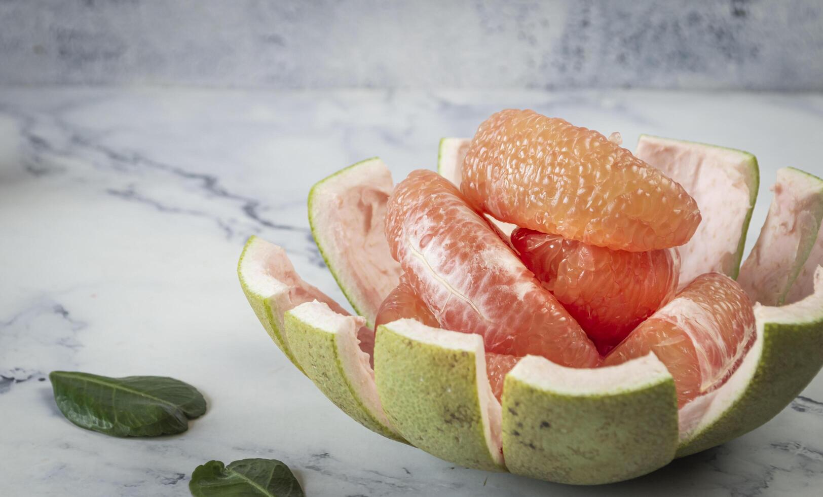 a bowl of sliced pomelo on a marble counter photo