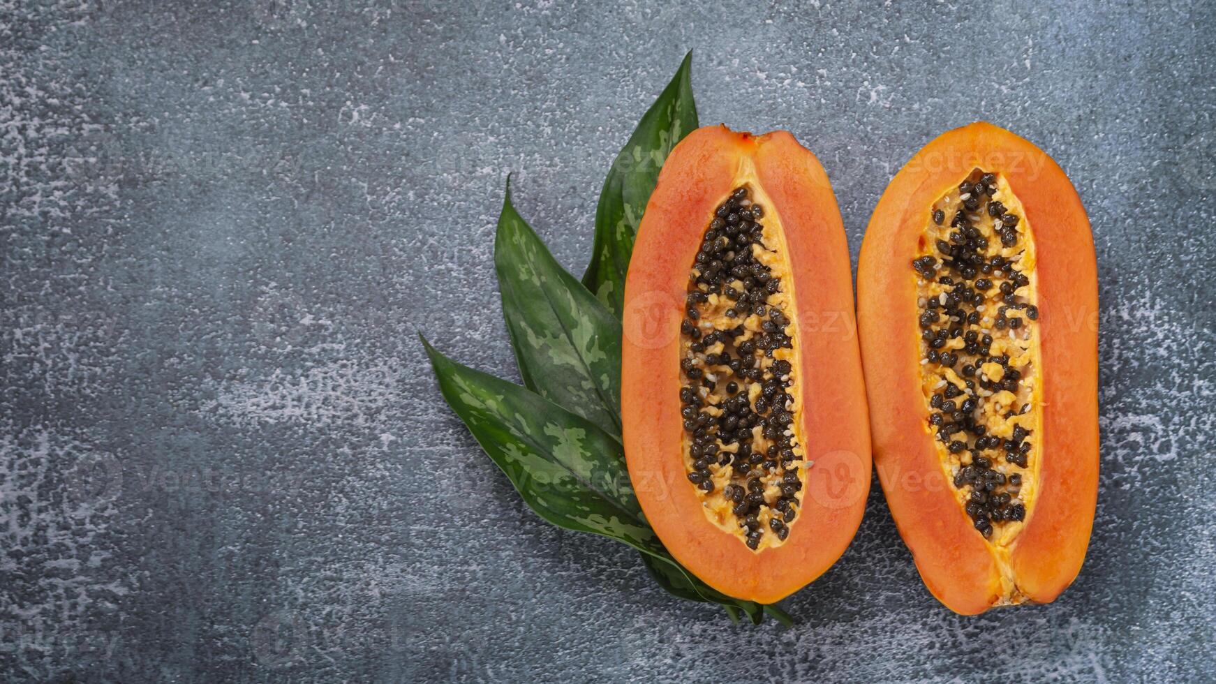 two papayas cut in half on a gray background photo