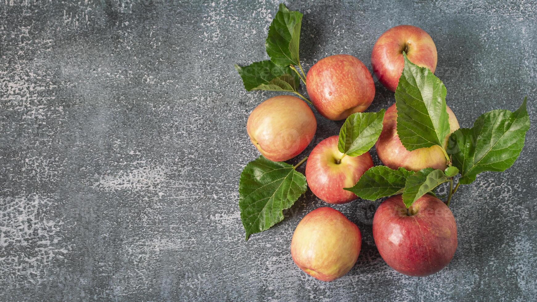 a bunch of apples with leaves on a gray background photo