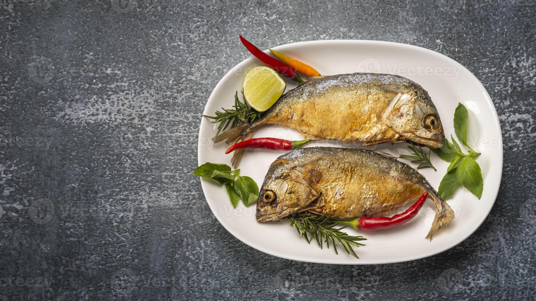 two short mackerel on a plate with herbs and spices photo