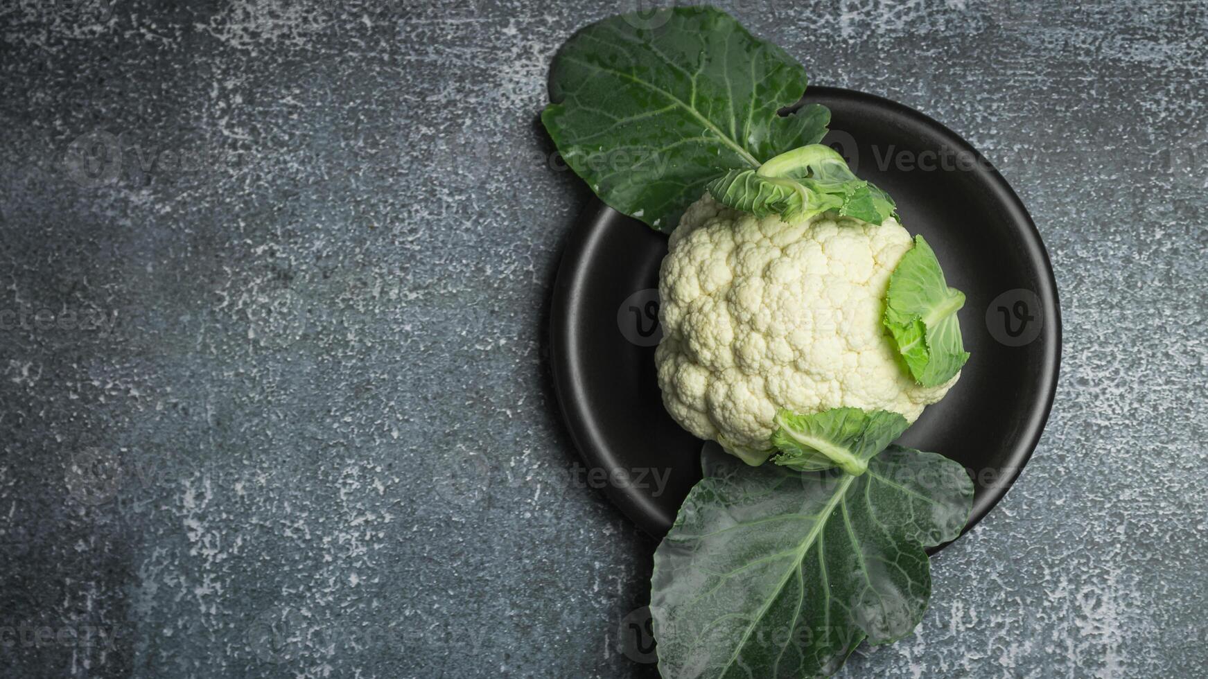fresh cauliflower on a black plate on a gray background photo