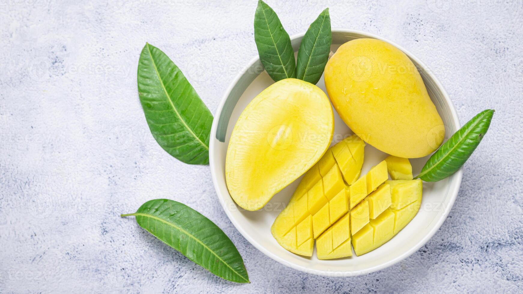 mango in a bowl with leaves on a blue background photo