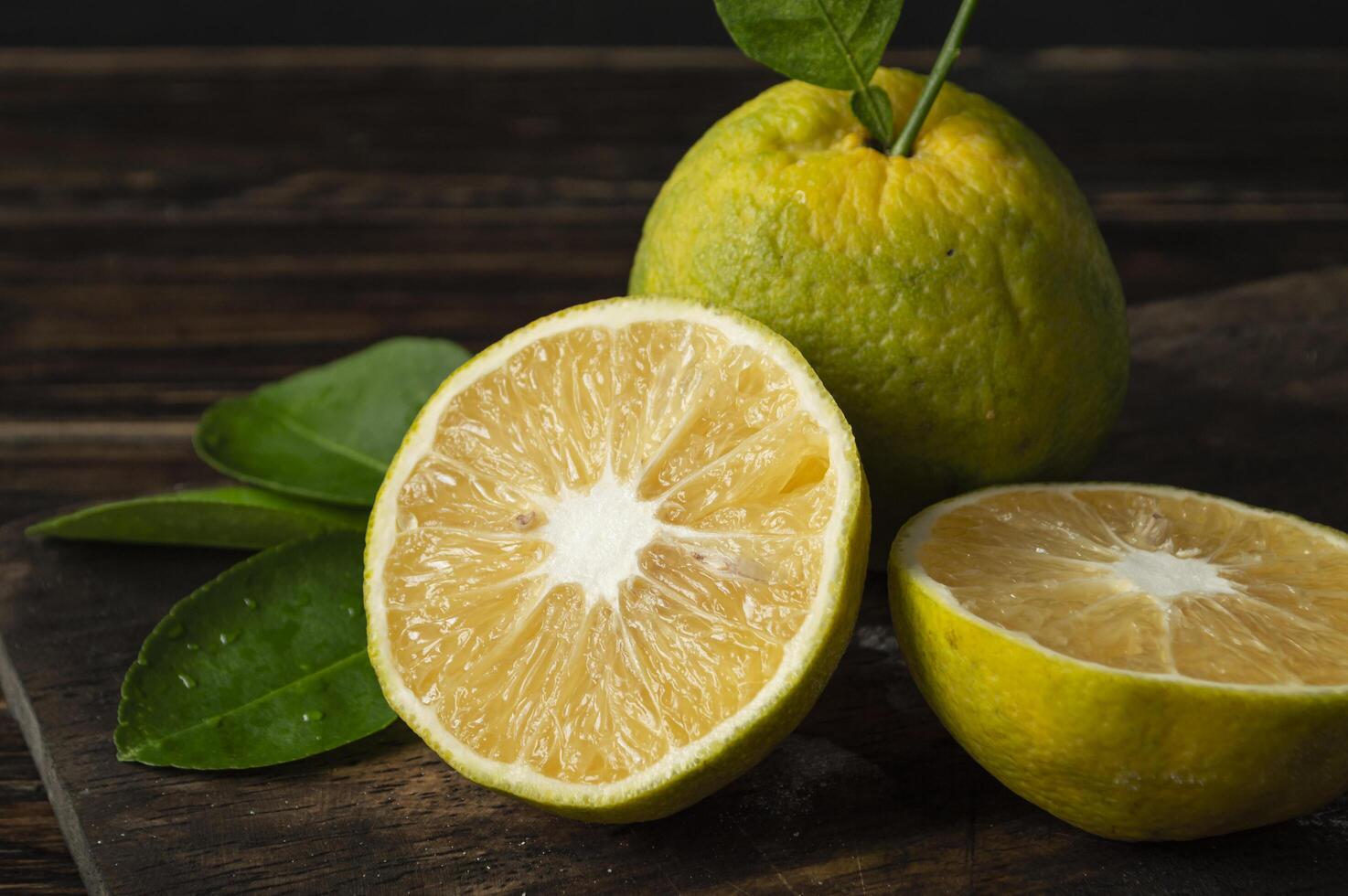 pomelo is cut in half and two halves are on a wooden board photo