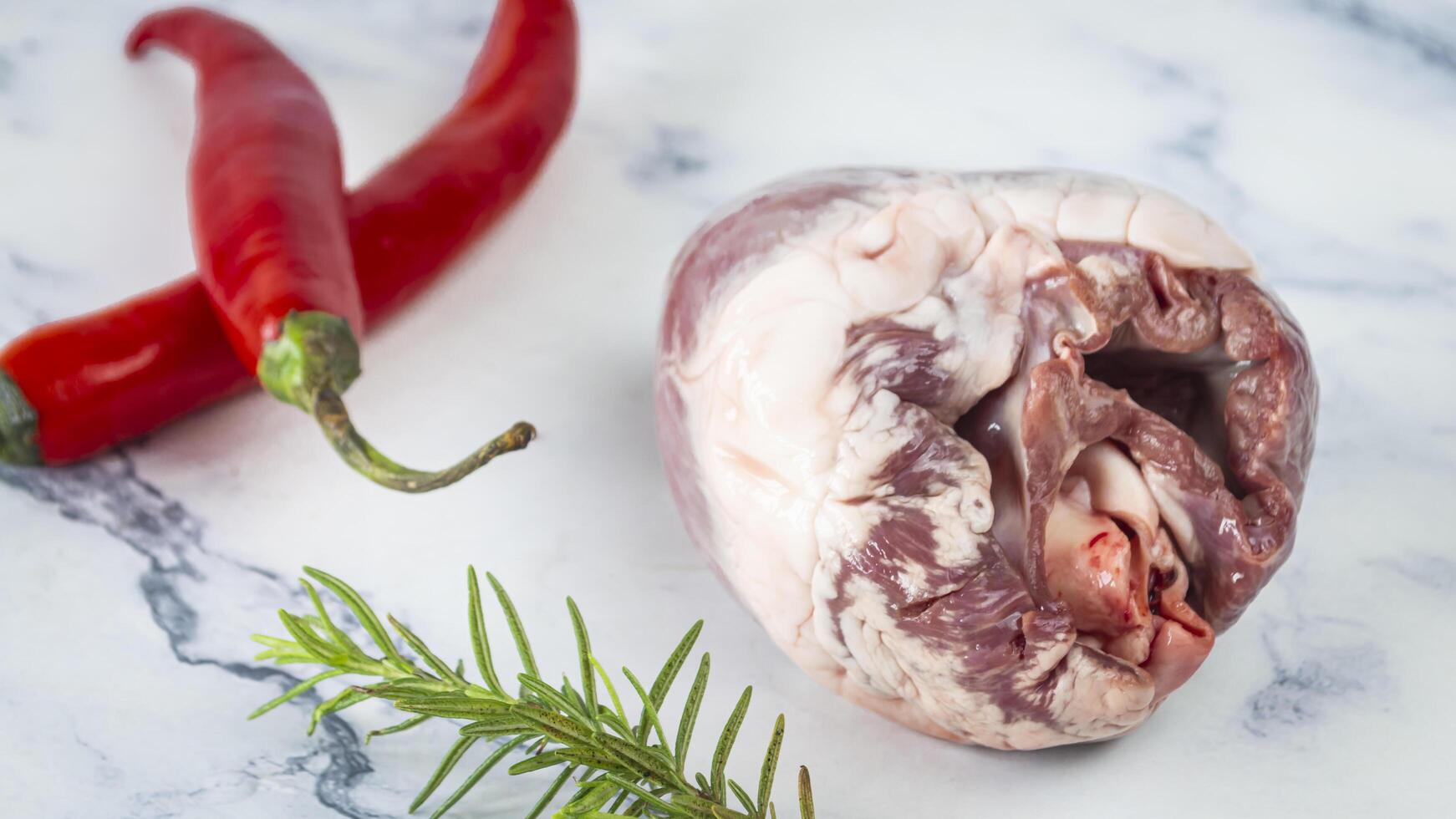 a piece of pig heart with a red pepper and rosemary photo