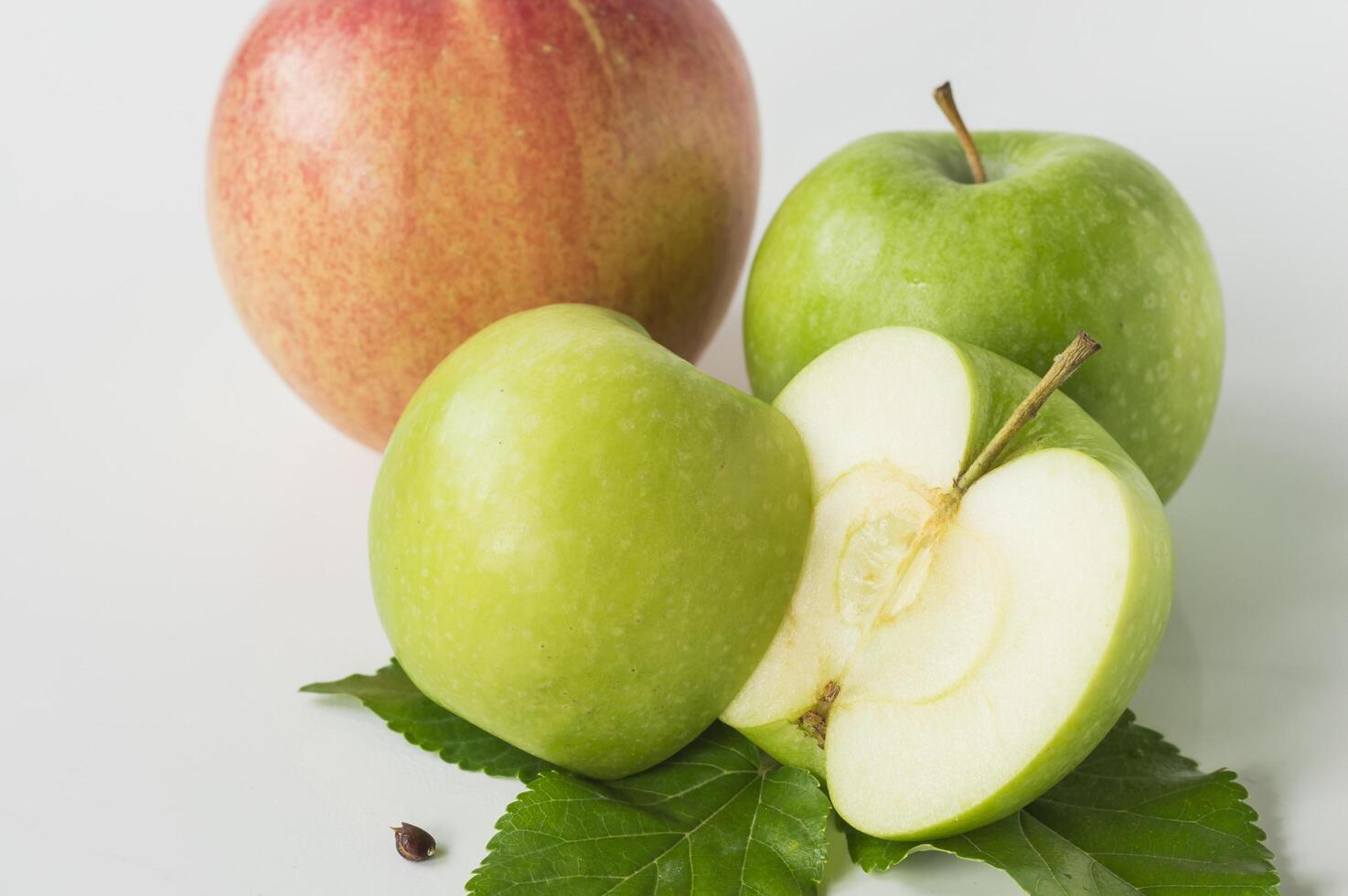 green apple with a slice cut in half and a green apple with a leaf photo