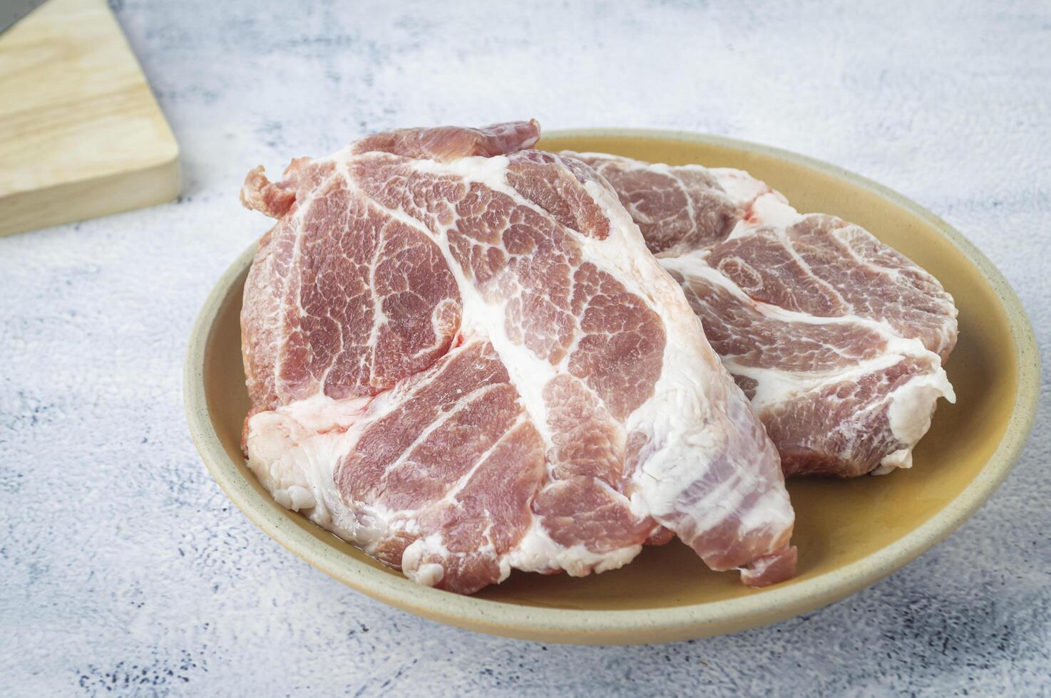 two raw pork chops on a plate with a knife photo