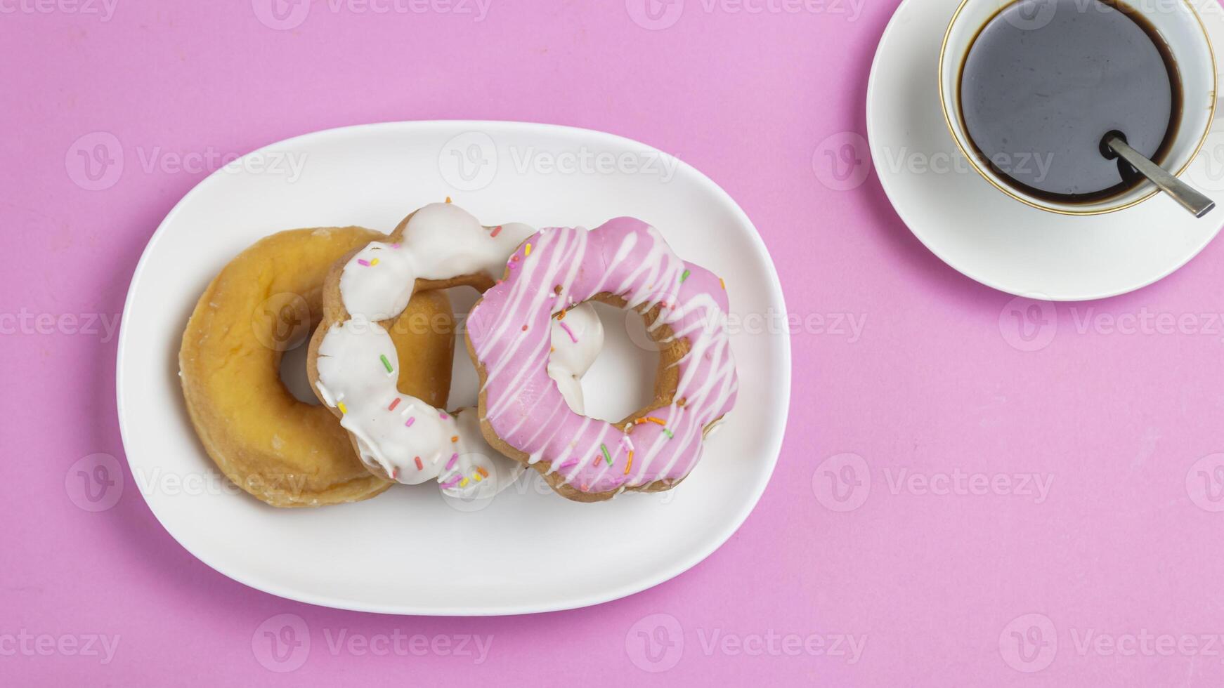 three donuts on a white plate with a cup of coffee photo